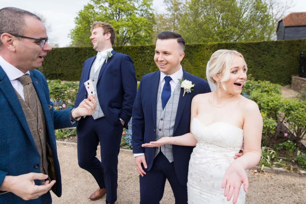 Bride and groom enjoying close-up magic at Blake Hall Essex wedding venue