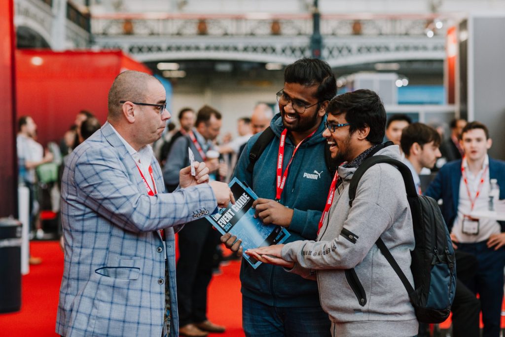 Award-winning trade show magician Andy Magicman performing close-up magic to engage visitors and generate conversations at a busy UK exhibition.