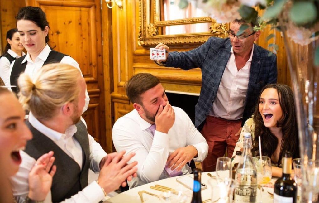 Corporate magician entertains guests with close up magic during dinner